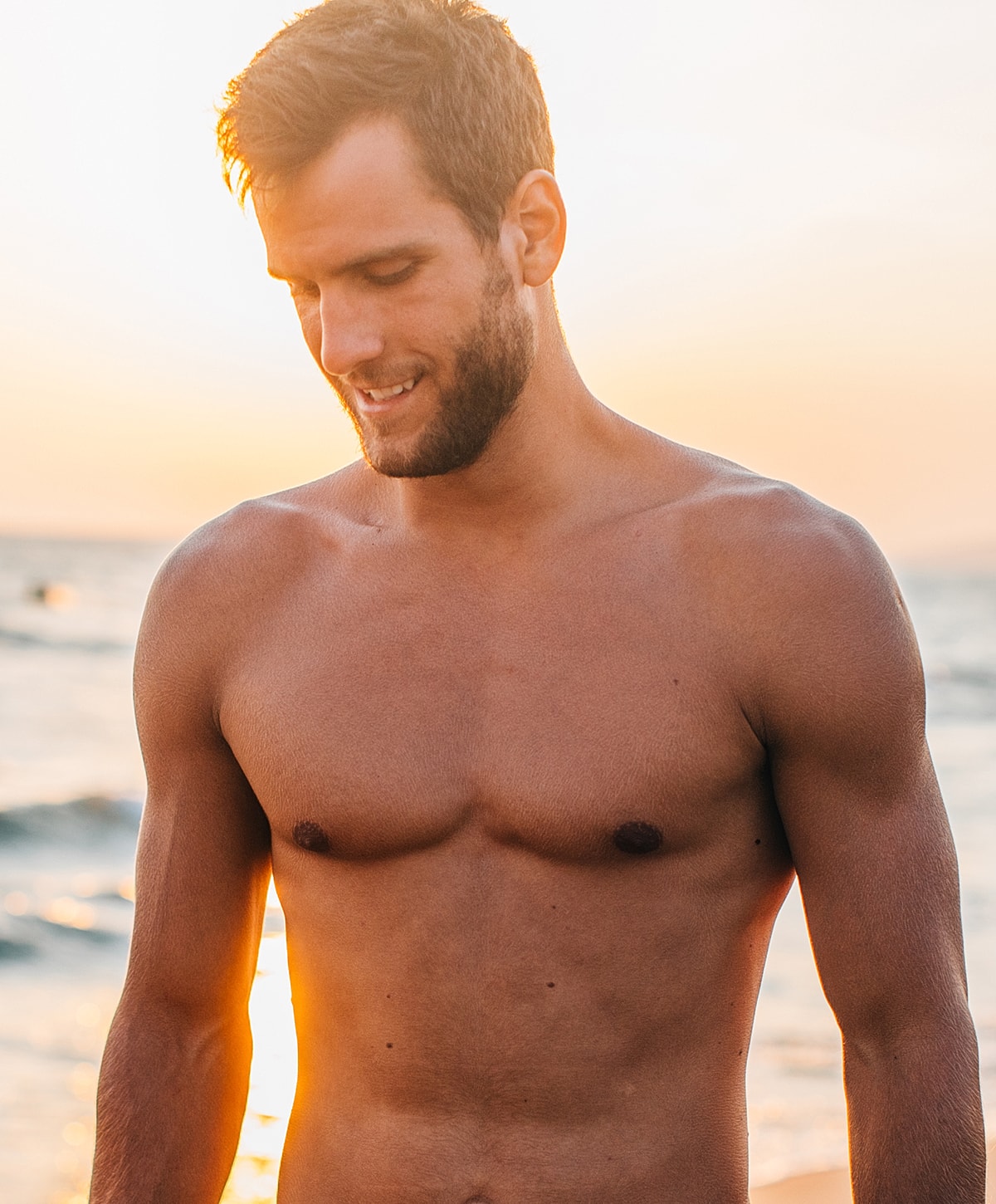 Man smiling at sunset on the beach.